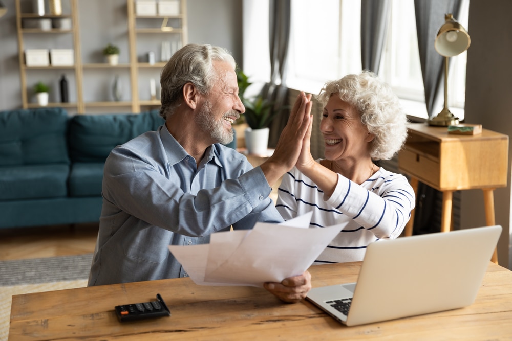 old couple giving high fives while working on taxes