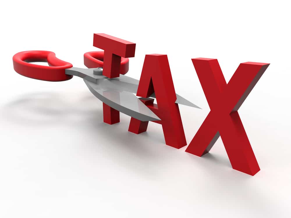 A 3D render of the word TAX is cut by a pair of scissors