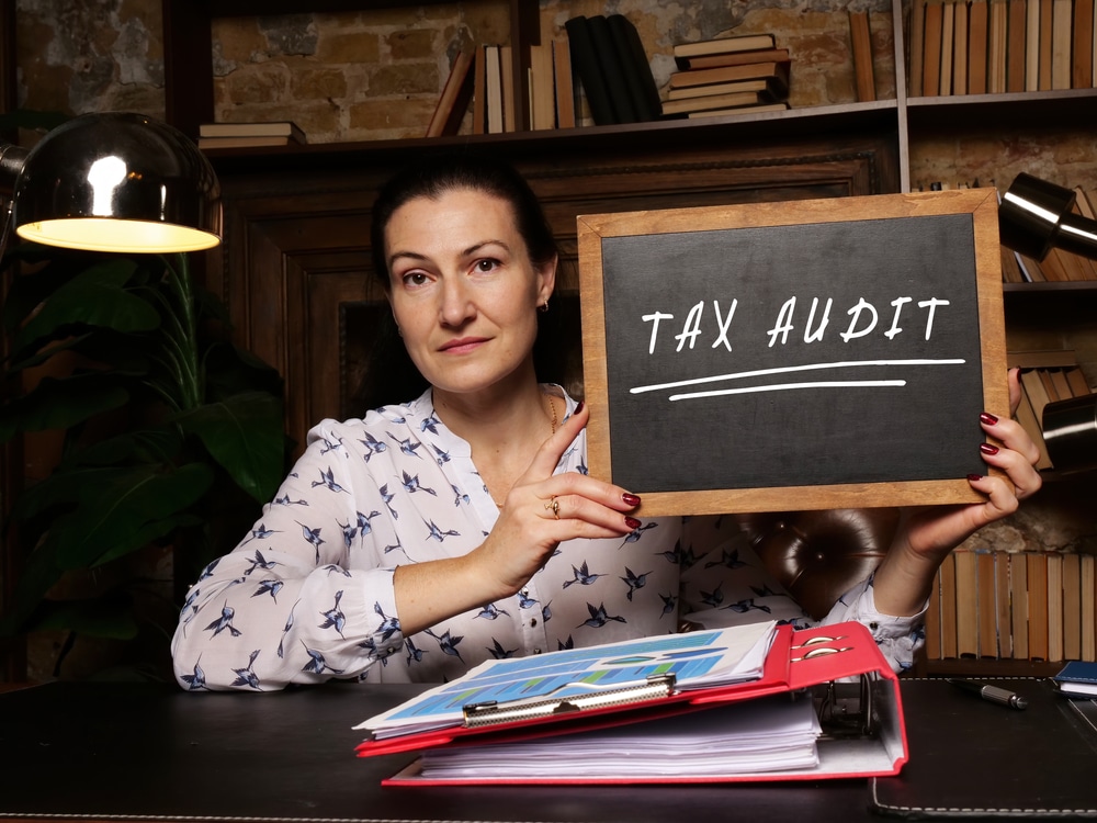 person holding a blackboard that says "TAX AUDIT"