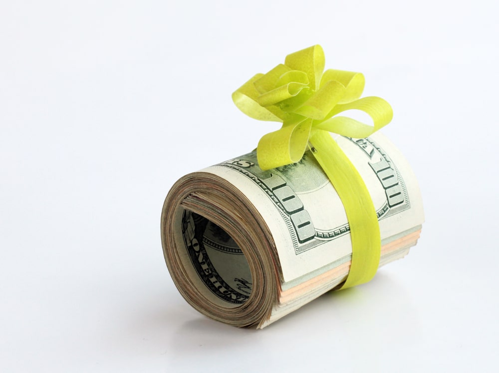 roll of money tied with a green ribbon as a gift